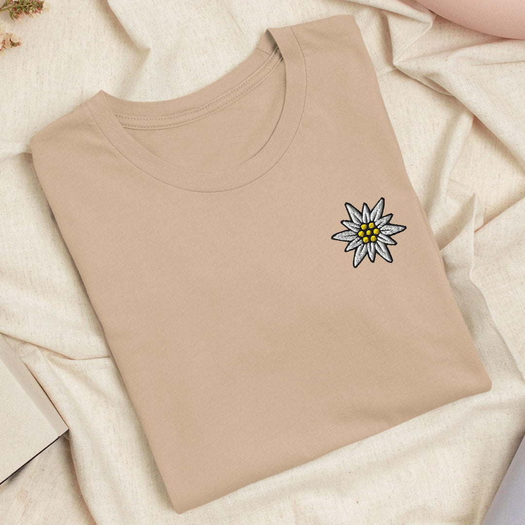 a t - shirt with a flower on it laying on a bed