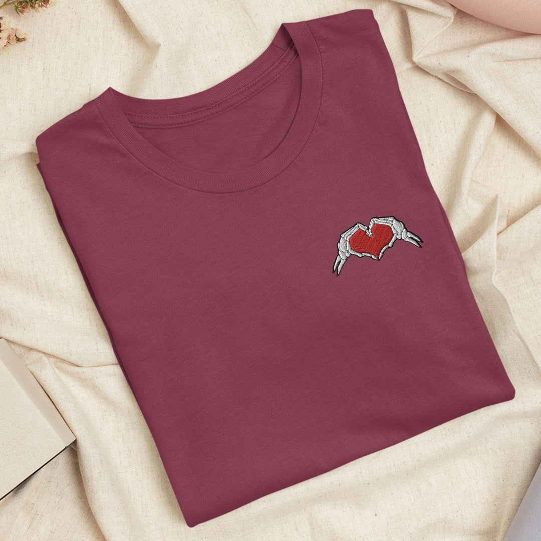 a red t - shirt with a heart and a bird embroidered on it