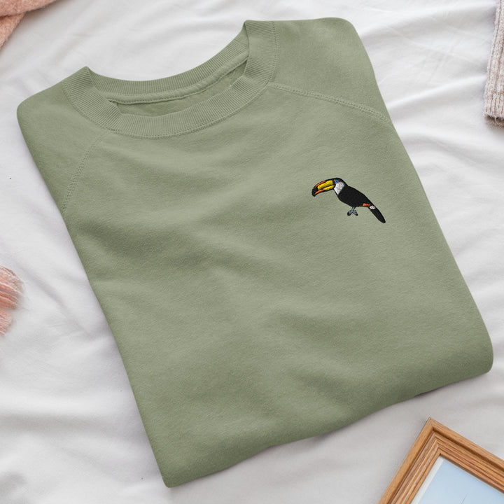 a green t - shirt with a toucan embroidered on it