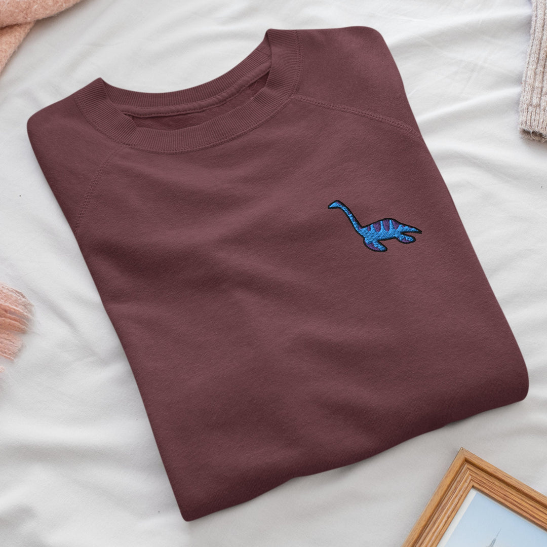 a t - shirt with a blue dinosaur embroidered on it
