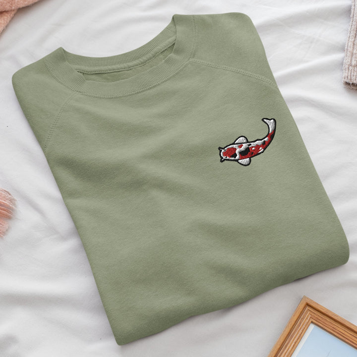 a green t - shirt with a koi fish embroidered on it