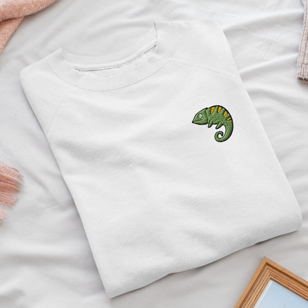 a white t - shirt with a green chamelon embroidered on it