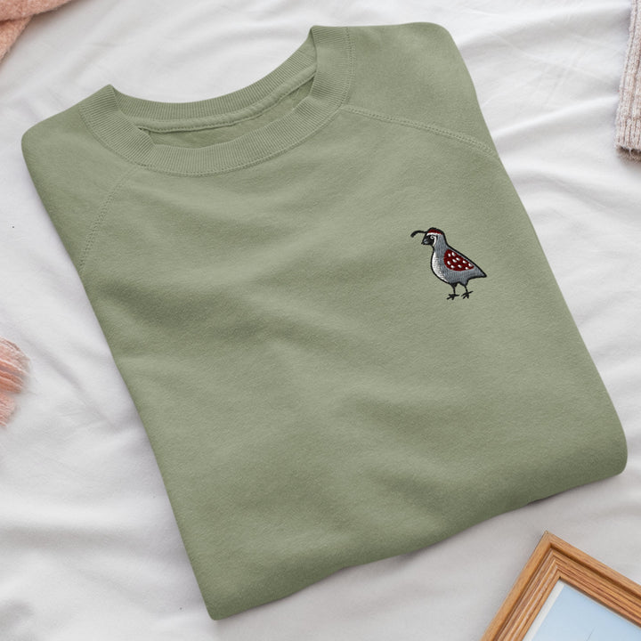 a green t - shirt with a bird embroidered on it