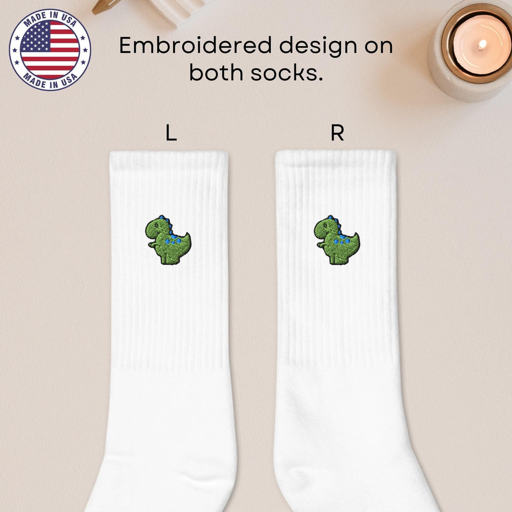 a pair of white socks with a green dinosaur on them