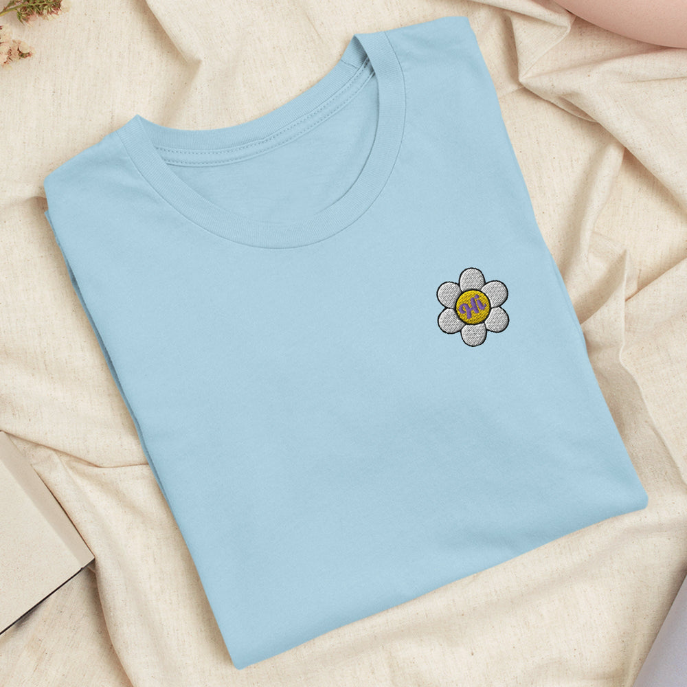 a blue t - shirt with a flower embroidered on it