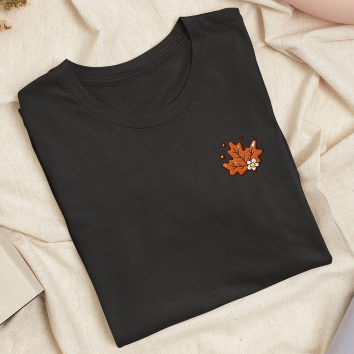 a black t - shirt with a maple leaf embroidered on it