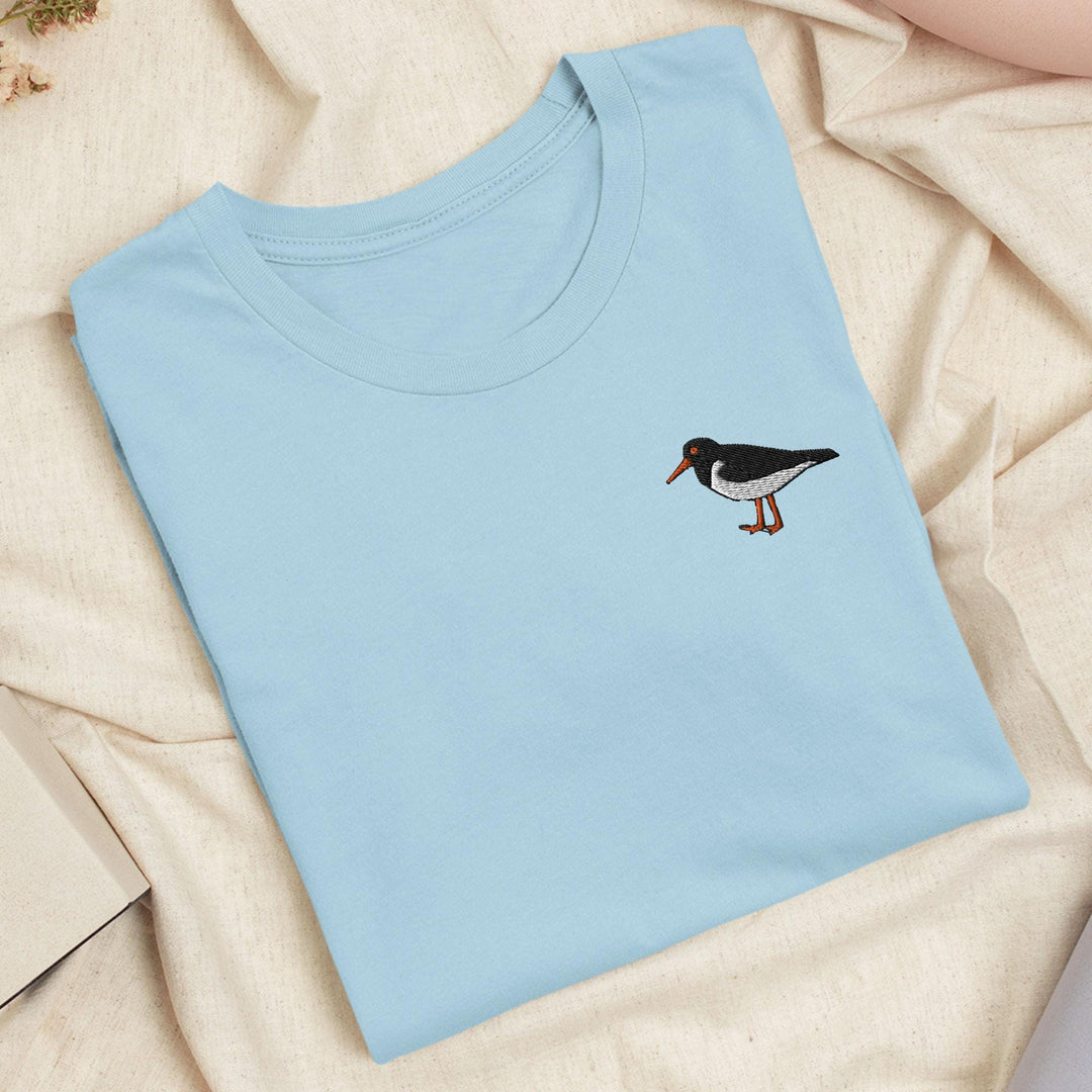 a blue t - shirt with a bird embroidered on it