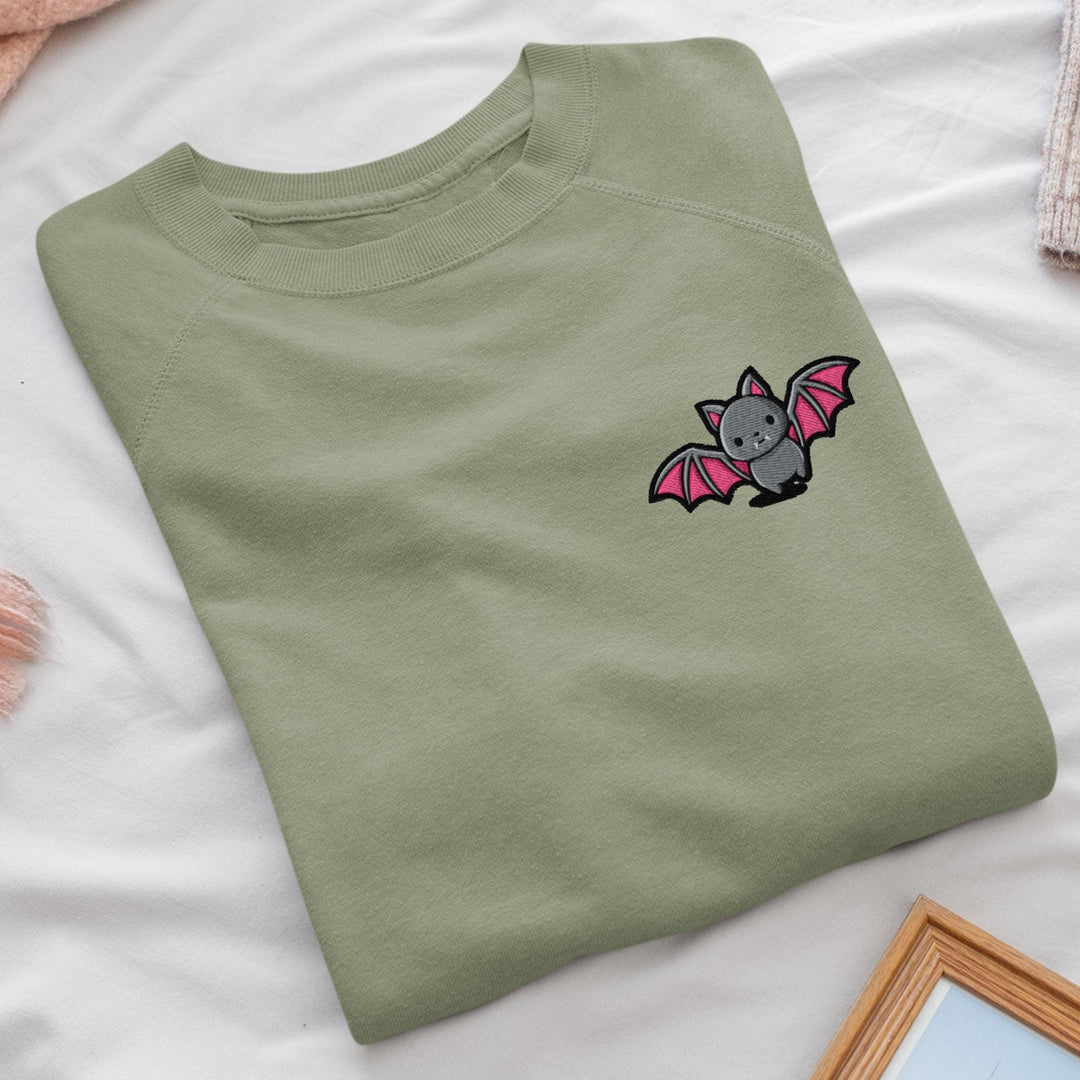 a green t - shirt with a bat embroidered on it