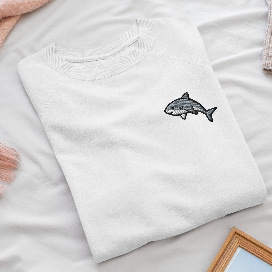 a white t - shirt with a shark embroidered on it