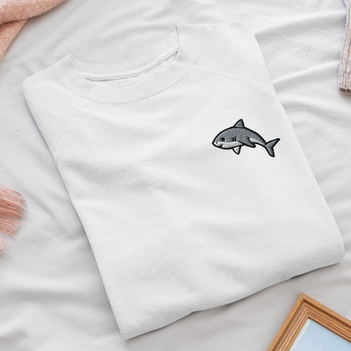 a white t - shirt with a shark embroidered on it